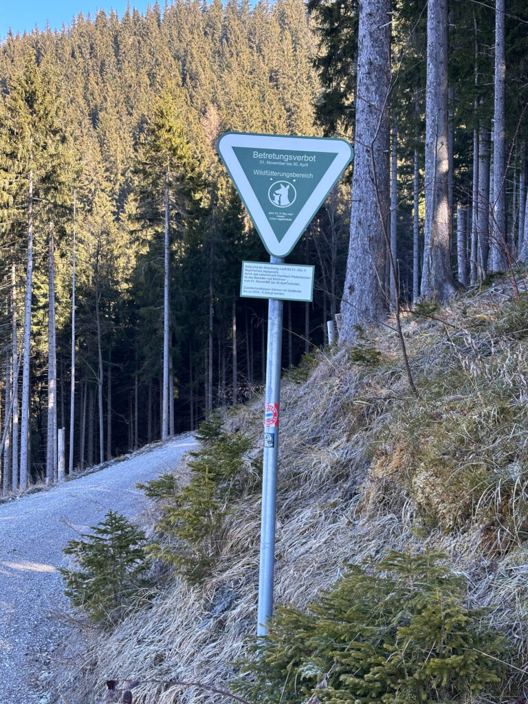 Grünes Schild am Wegesrand mit Hinweis auf das Betretungsverbot im Wildfütterungsbereich beziehungsweise Wildschutzgebiet.